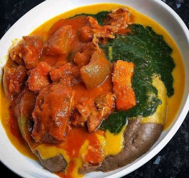 Authentic Nigerian amala served with ewedu, gbegiri and assorted meat on a traditional plate